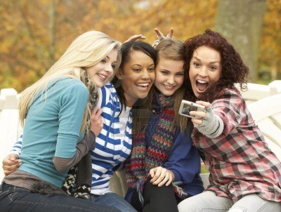 7175740-groupe-de-quatre-filles-adolescentes-se-prendre-en-photo-avec-camera-assis-sur-le-banc-en-automne-pa
