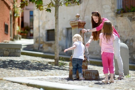 Niños y madre jugando en la fuente